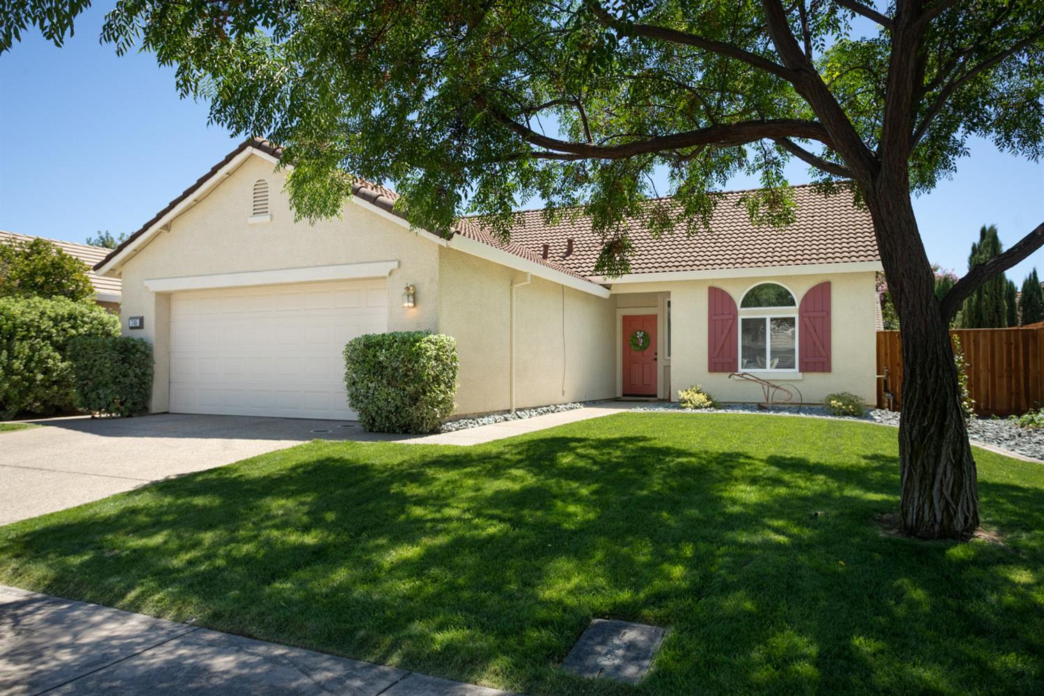 a view of a white house with a big yard plants and large trees