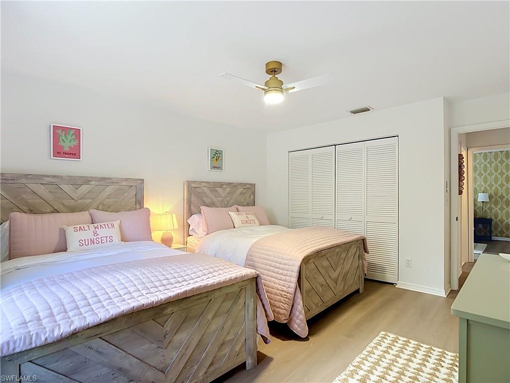 812 102nd Avenue North Naples, FL 34108 - Photo 25 of 33 Wood-finish flooring, white louvered bifold closet doors, and a gold-tone ceiling fan with integrated lighting