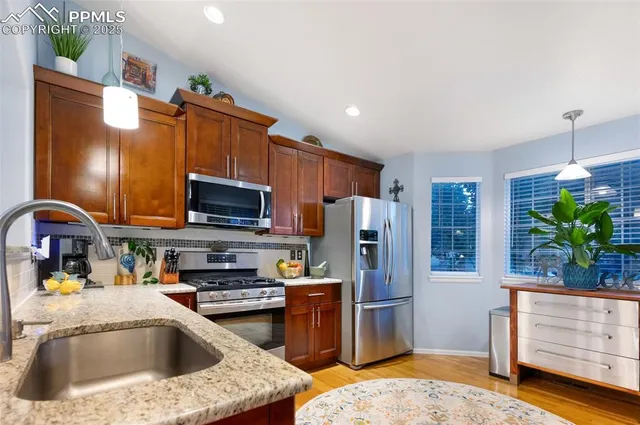 a kitchen with a sink stainless steel appliances a refrigerator a stove and cabinets