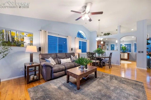 a living room with furniture kitchen view and a wooden floor