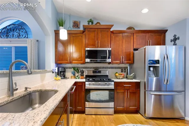 a kitchen with granite countertop a refrigerator stove and sink