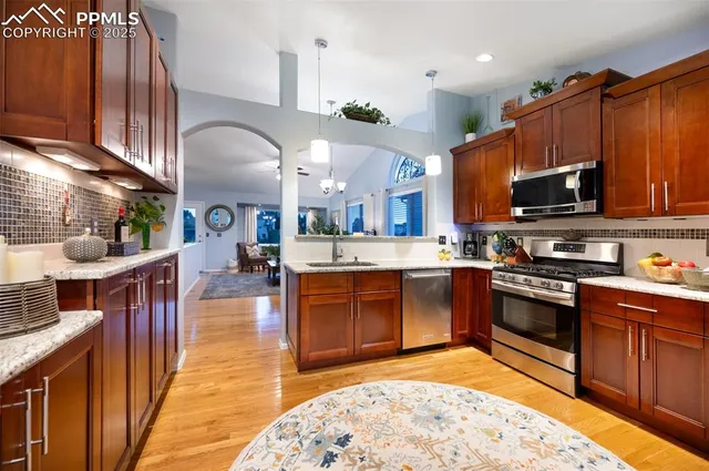 a kitchen with stainless steel appliances granite countertop a stove top oven a sink dishwasher and cabinets with wooden floor