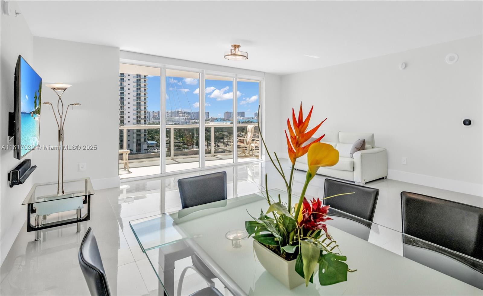 18911 Collins Avenue, Unit 1003 Sunny Isles Beach, FL 33160 - Photo 6 of 47 a living room with furniture a flat screen tv and a floor to ceiling window