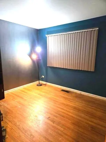 a view of empty room with window and wooden floor