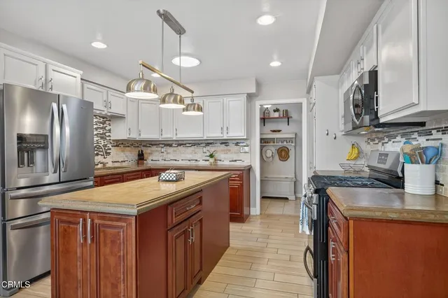 a kitchen with kitchen island granite countertop a sink cabinets and stainless steel appliances