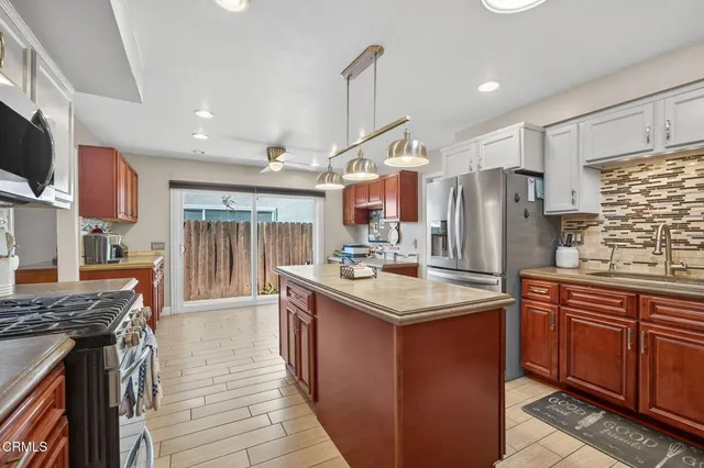a kitchen with stainless steel appliances granite countertop a stove top oven a refrigerator and cabinets