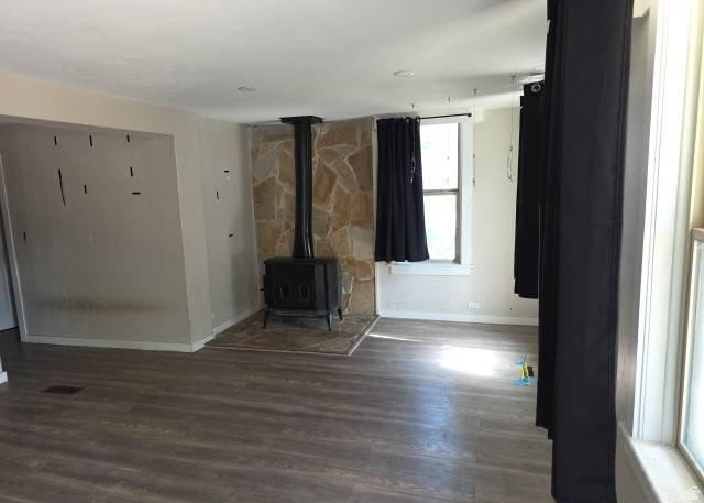 3161 Adams Avenue Ogden, UT 84403 - Photo 5 of 17 Living space featuring wood-finish flooring, a stone accent wall, and a freestanding wood-burning stove with a stone hearth