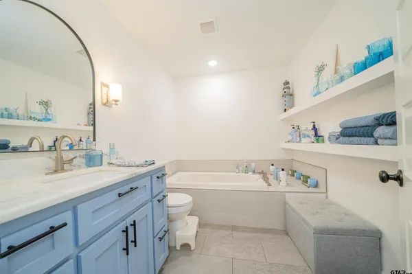 a bathroom with a granite countertop sink a toilet and mirror