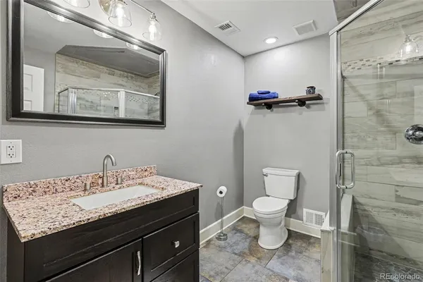 a bathroom with a granite countertop sink a toilet and a mirror