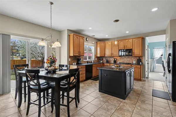 a kitchen with stainless steel appliances granite countertop wooden cabinets a refrigerator a stove a sink a dining table and chairs