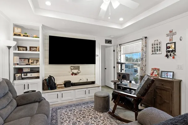 a living room with furniture a flat screen tv and a floor to ceiling window