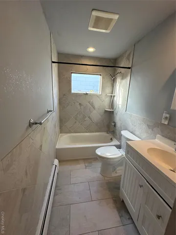 a bathroom with a granite countertop bathtub shower sink vanity and toilet