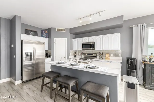 a kitchen with a refrigerator a stove a sink and chairs