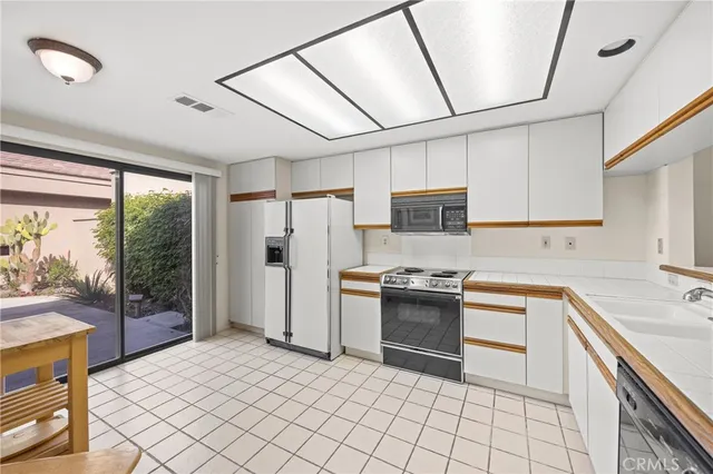 a kitchen with stainless steel appliances granite countertop a refrigerator a sink dishwasher a stove top oven and a dining table with wooden floor