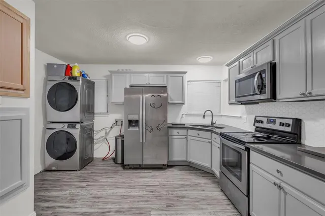 a kitchen with stainless steel appliances a stove a sink dishwasher a refrigerator and wooden cabinets