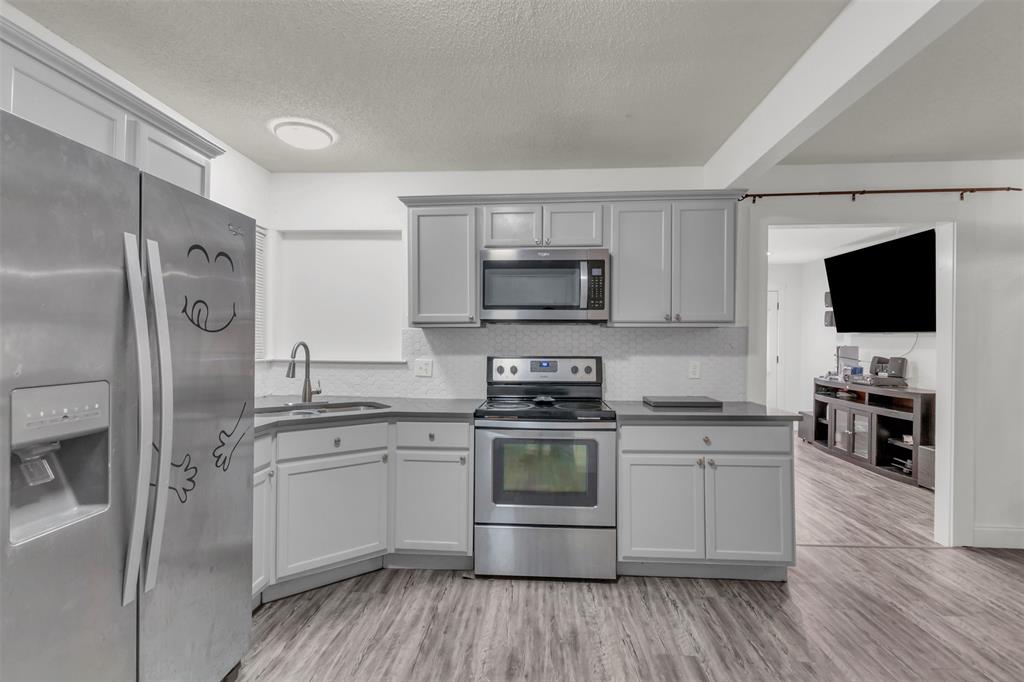 929 North Hall Street Lancaster, TX 75146 - Photo 10 of 24 a kitchen with stainless steel appliances a sink cabinets and a wooden floor