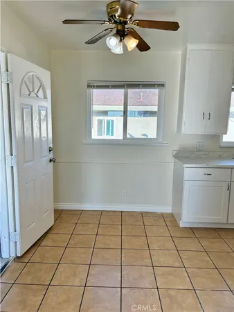 a view of an empty room with window and chandelier fan