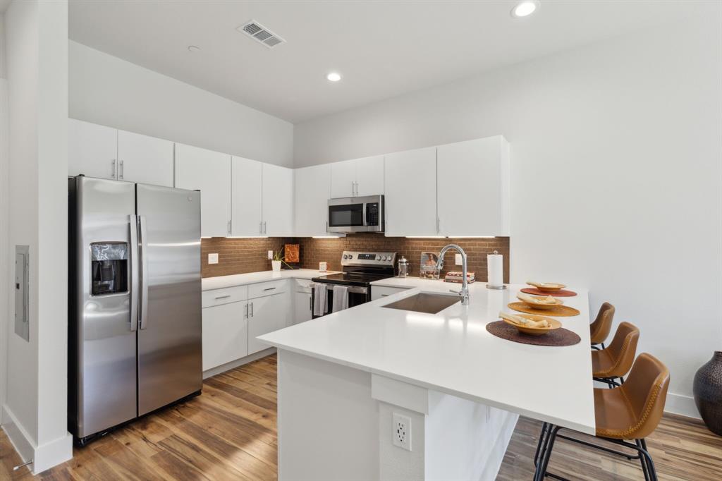 2990 Reagan Street Dallas, TX 75219 - Photo 4 of 20 a kitchen with stainless steel appliances granite countertop a refrigerator a stove a sink and a microwave