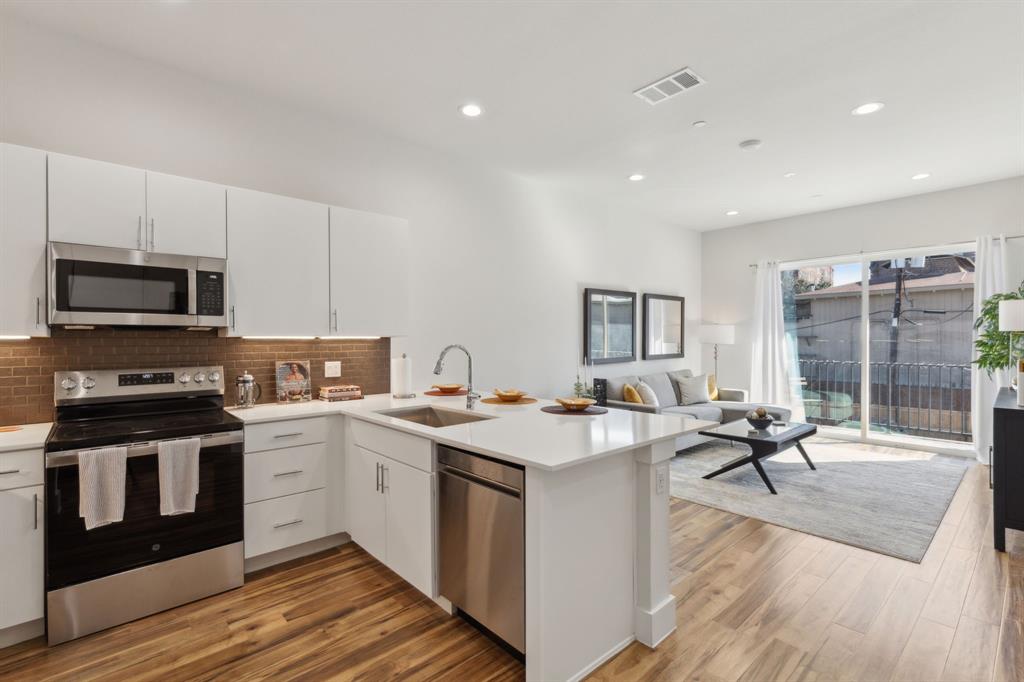2990 Reagan Street Dallas, TX 75219 - Photo 5 of 20 a open kitchen with stainless steel appliances granite countertop a stove top oven a sink dishwasher a dining table and chairs with wooden floor