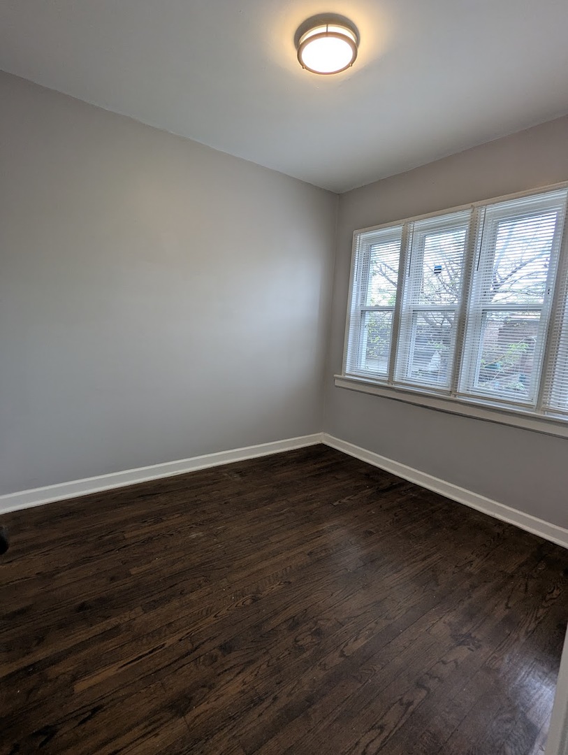 7545 South May Street Chicago, IL 60620 - Photo 12 of 18 a view of an empty room with wooden floor and a window