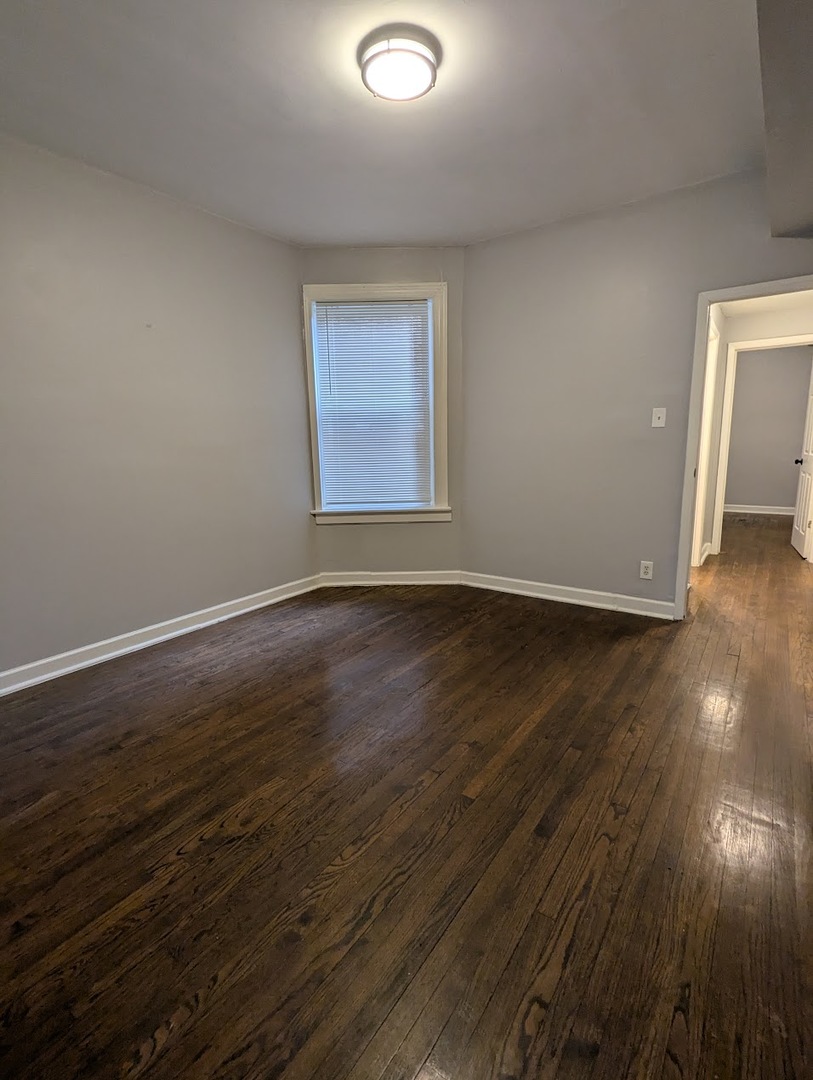 7545 South May Street Chicago, IL 60620 - Photo 9 of 18 a view of an empty room with wooden floor and a window