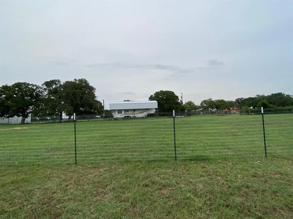 a view of a green field with wooden fence