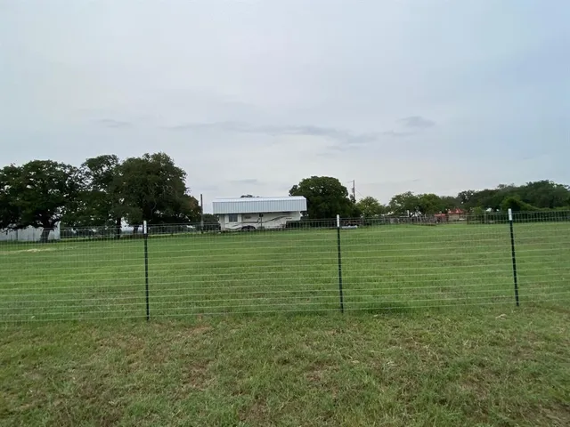 a view of a green field with wooden fence