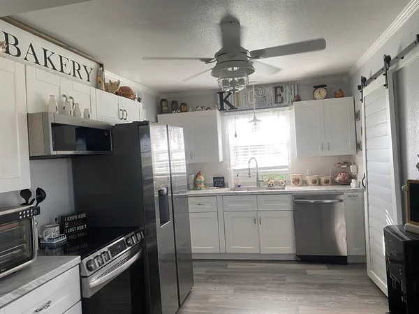 a kitchen with stainless steel appliances granite countertop a sink a stove a refrigerator cabinets and a window