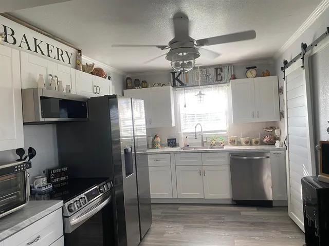 a kitchen with stainless steel appliances granite countertop a sink a stove a refrigerator cabinets and a window