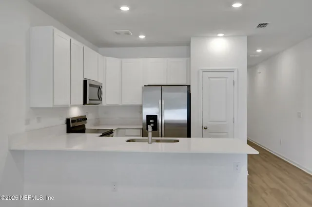 a kitchen with kitchen island a sink stainless steel appliances and cabinets