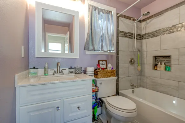 a bathroom with a granite countertop sink toilet mirror vanity and bathtub