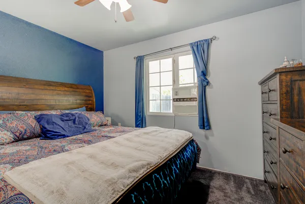a bedroom with a bed a dresser and a chandelier