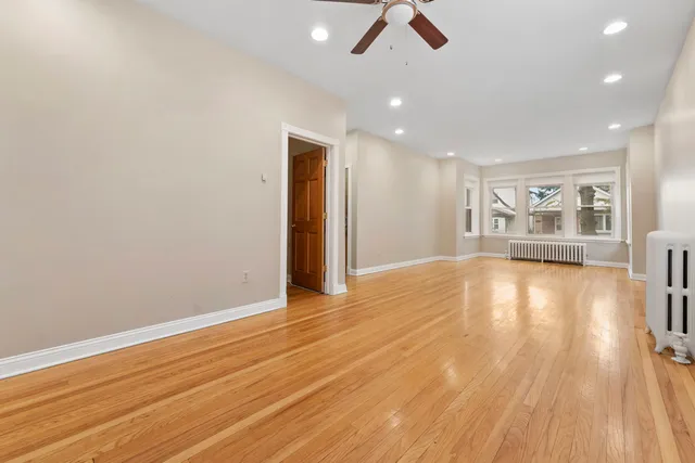 a view of empty room with wooden floor and fan