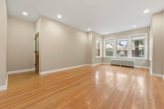 a view of an empty room with a window and wooden floor