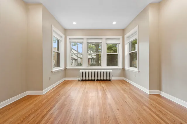 a view of an empty room with a window and wooden floor