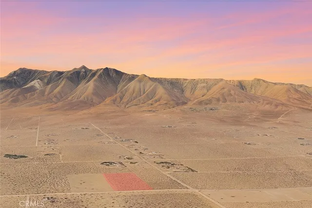 a view of a dry yard with mountains in the background