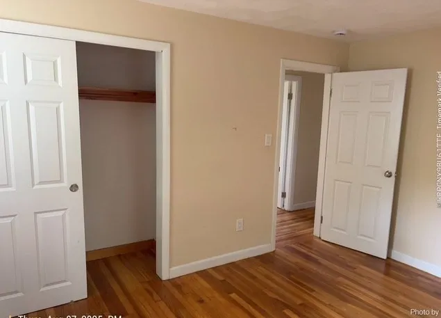 an empty room with wooden floor and closet area