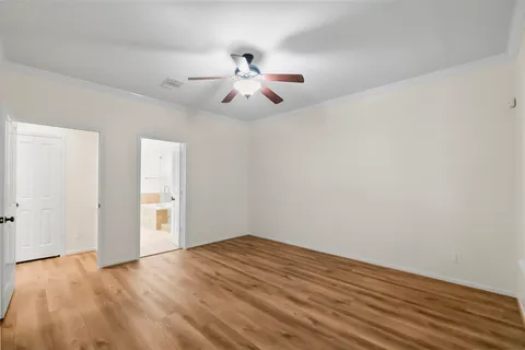 an empty room with wooden floor fan and windows