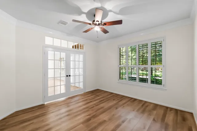 an empty room with wooden floor fan and windows