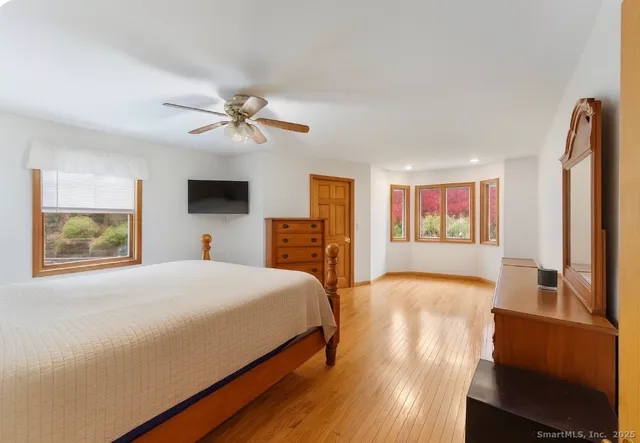 a bedroom with a bed and dresser with wooden floor