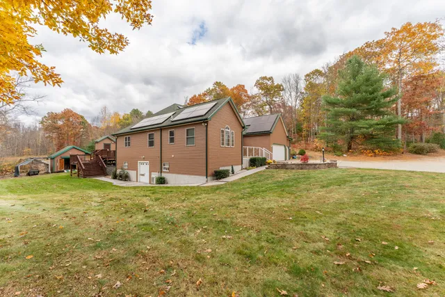 a view of a big house with a big yard and large trees