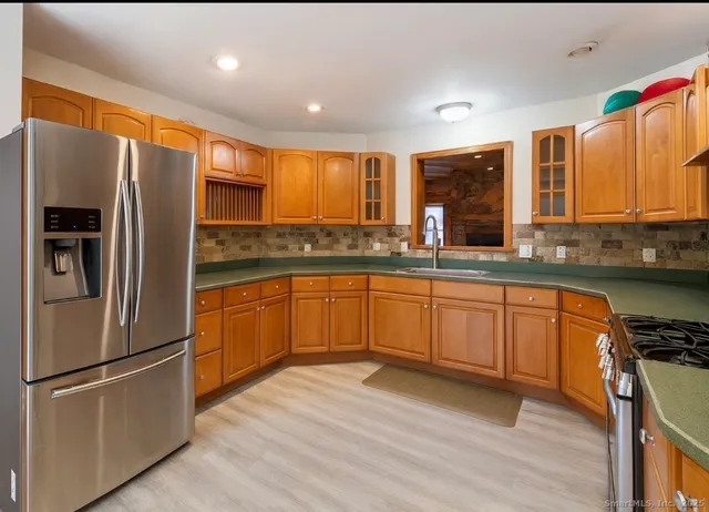 a kitchen with stainless steel appliances granite countertop a refrigerator a sink dishwasher a stove with wooden cabinets and floor