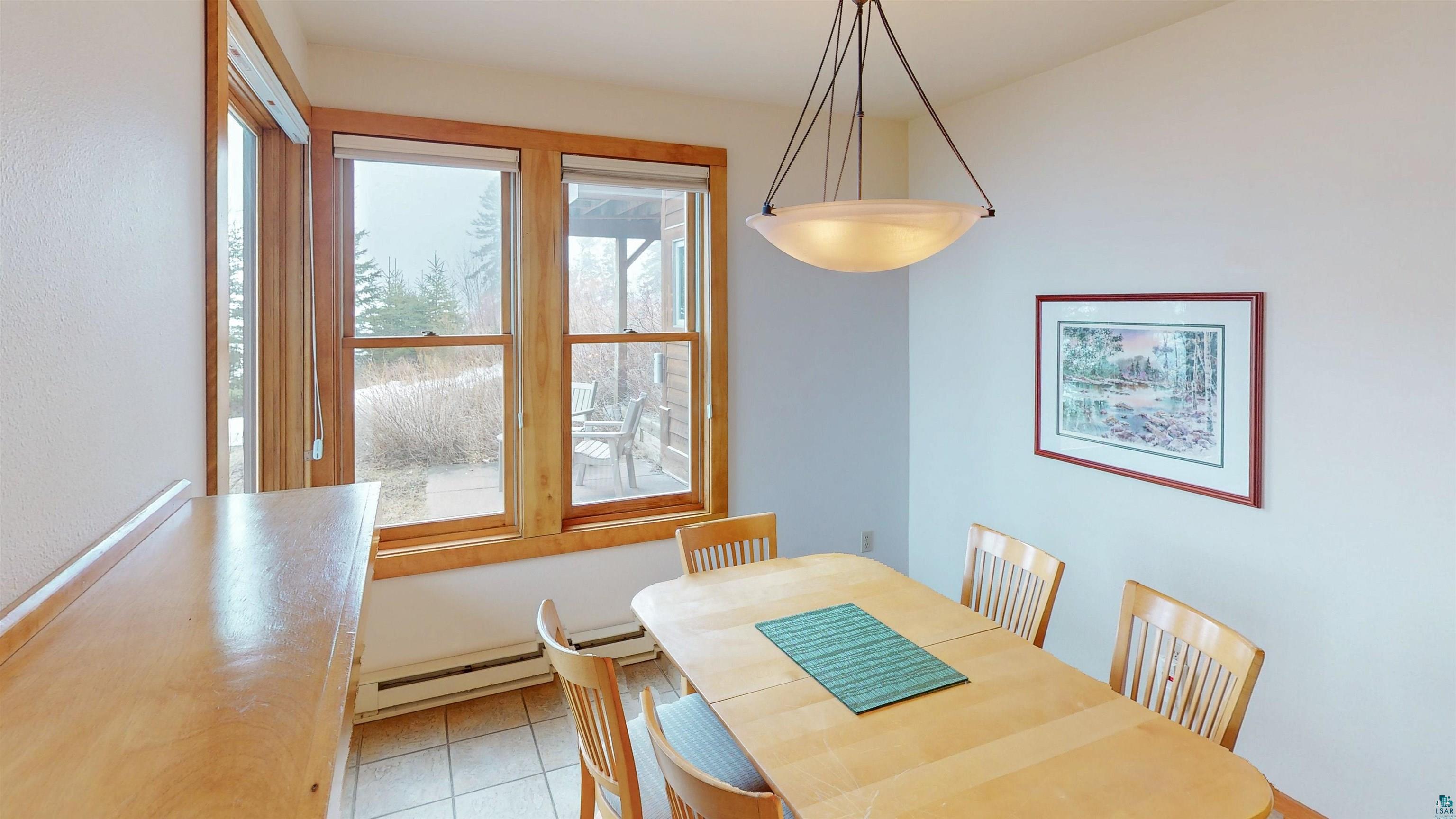 504-506 Poplar River Road, Unit 505 Lutsen, MN 55612 - Photo 5 of 39 Dining area featuring an overhead bowl pendant light fixture, tile flooring, and a bank of windows with natural wood trim