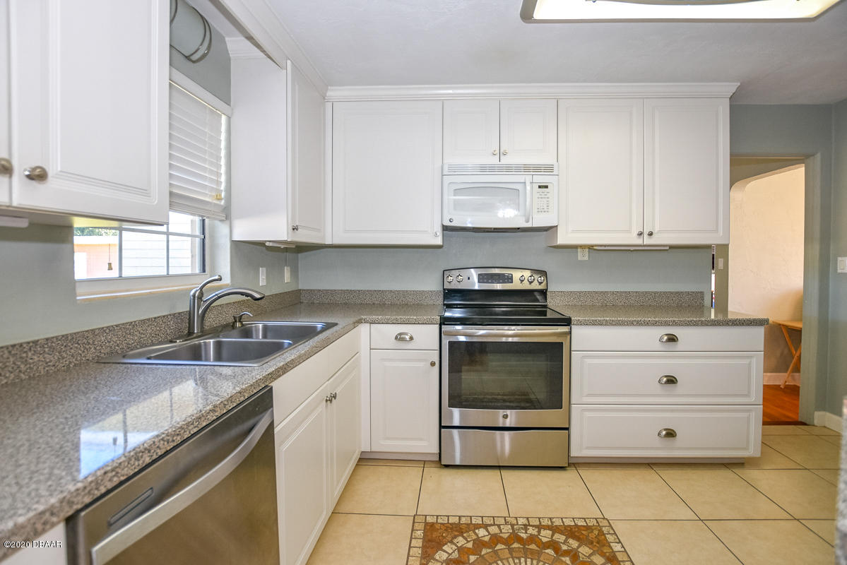 1509 Ridge Avenue Holly Hill, FL 32117 - Photo 11 of 40 a kitchen with granite countertop a stove sink and cabinets