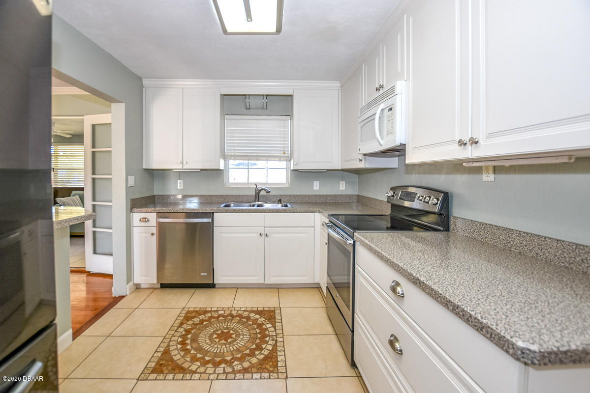1509 Ridge Avenue Holly Hill, FL 32117 - Photo 12 of 40 a kitchen with granite countertop white cabinets and white appliances