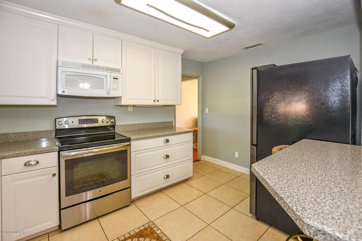 1509 Ridge Avenue Holly Hill, FL 32117 - Photo 15 of 40 a kitchen with granite countertop white cabinets and white appliances