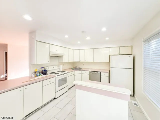 a kitchen with a sink a refrigerator and white cabinets