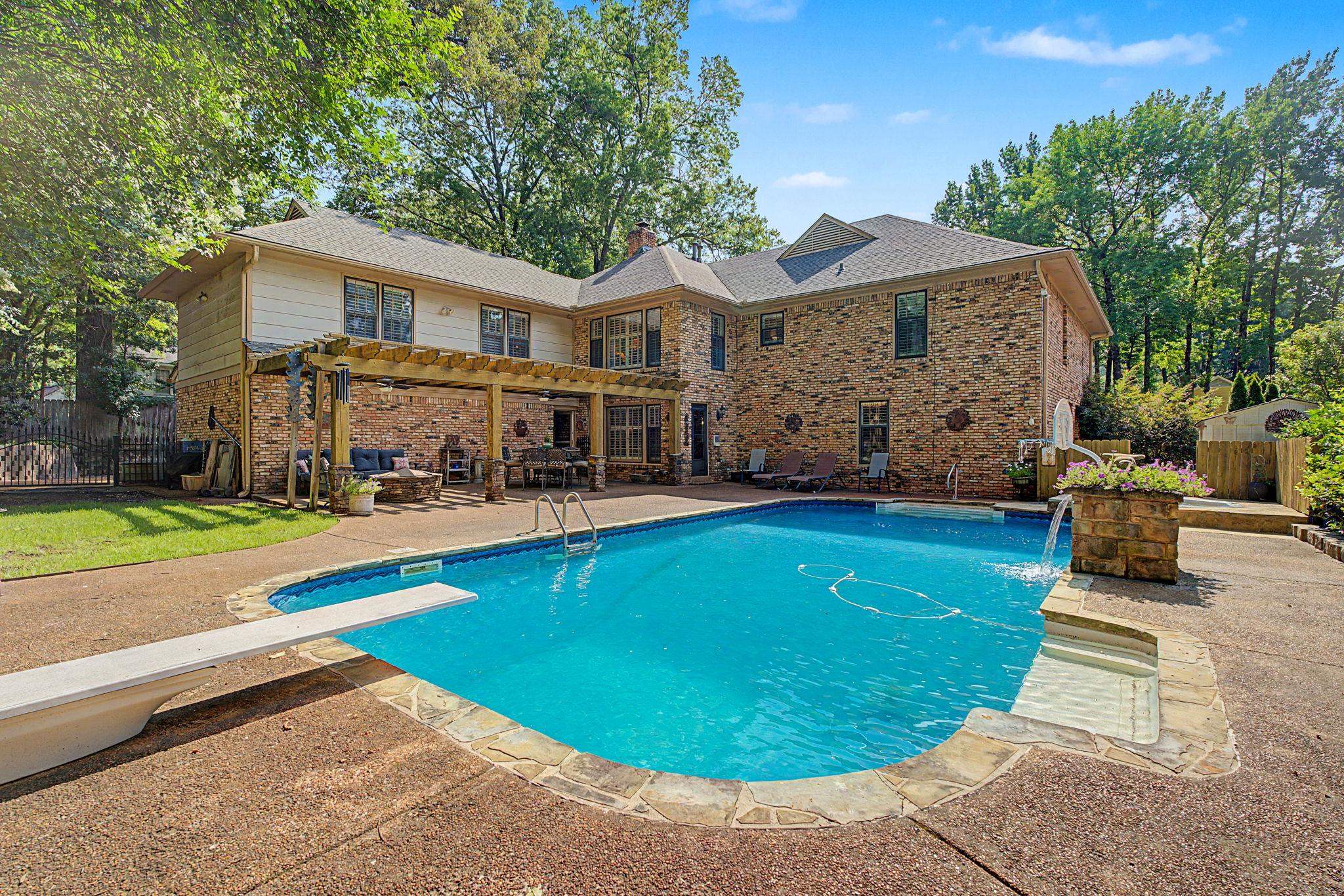 1929 Miller Farms Road Germantown, TN 38138 - Photo 37 of 40 Brick exterior residence featuring a curved swimming pool, diving board, and stone coping
