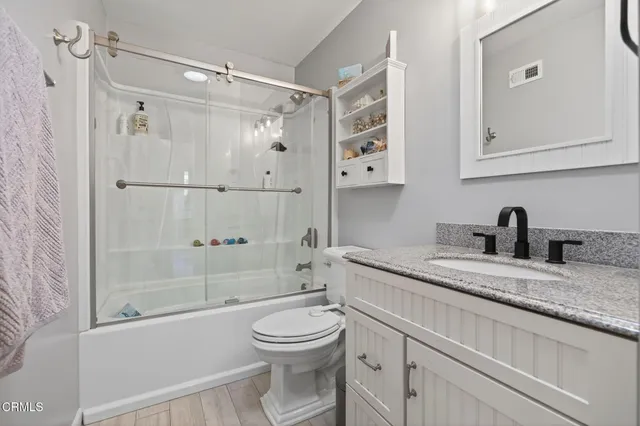 a bathroom with a granite countertop sink toilet and shower