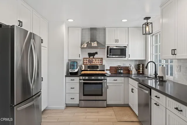 a kitchen with stainless steel appliances granite countertop a stove a refrigerator and a sink